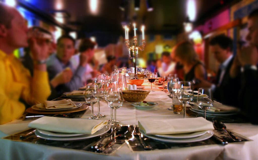 Guests sit at table set with dishes and glasses