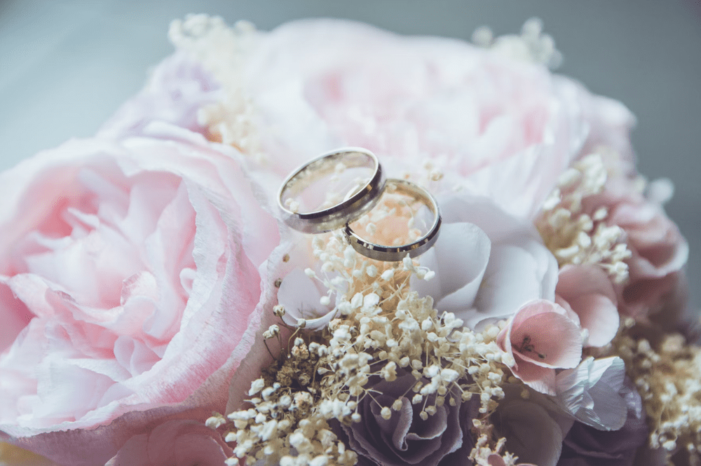 Two wedding rings on top of a bouquet of roses