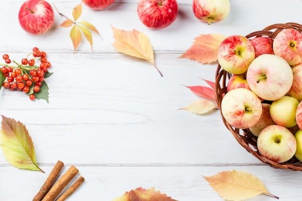 Autumn fall flat lay composition with ripe red apples, yellow leaves, cinnamon