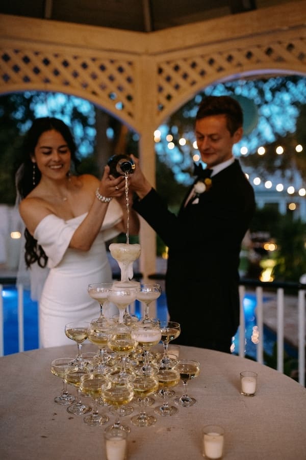 Bride and groom pour champagne over a champagne tower