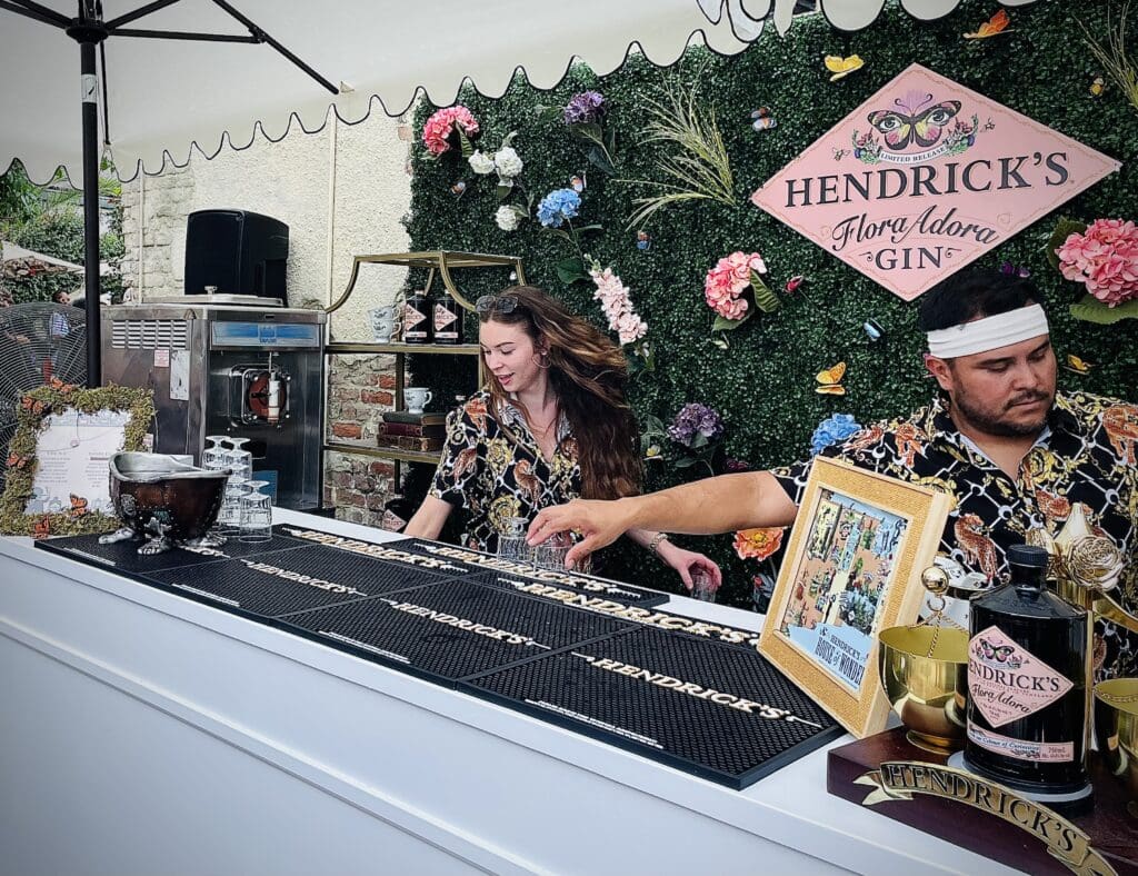 Bartenders at Hendrick's event, with flower wall behind bar