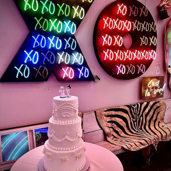 New Orleans wedding cost symbolized by a wedding cake under a neon XO sign.